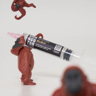 Orangutan Trading Co spore syringe with three toy orangutans playing with it, white background