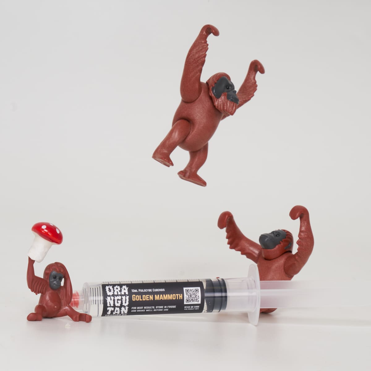 Orangutan Trading Co spore syringe with three toy orangutans playing with it, white background