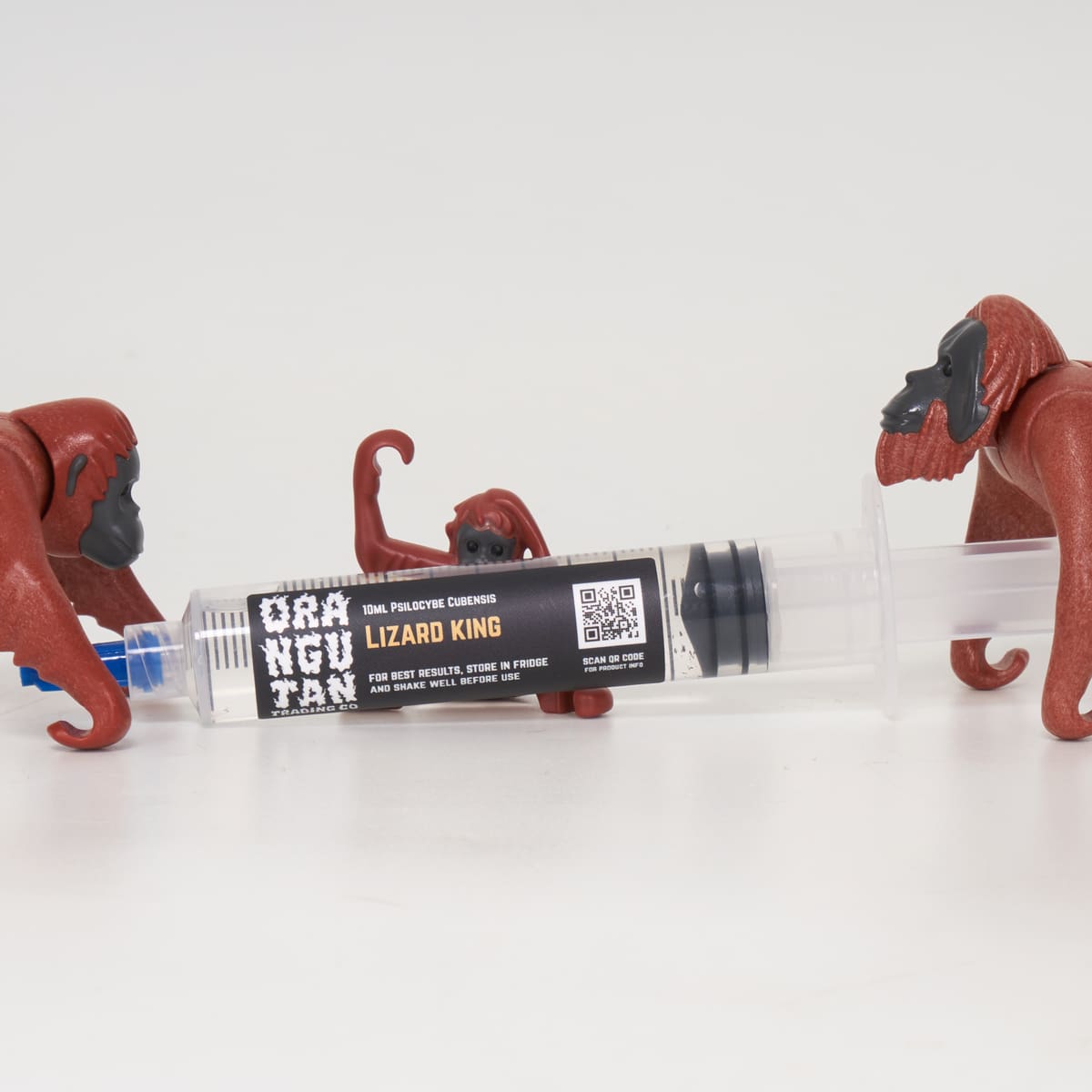 Orangutan Trading Co spore syringe with three toy orangutans playing with it, white background