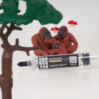 Orangutan Trading Co spore syringe with three toy orangutans playing with it, white background