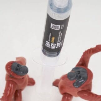 Orangutan Trading Co spore syringe with two toy orangutans playing with it, white background